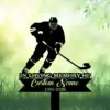 Silhouette of a hockey player with stick and puck above a memorial sign reading "In Loving Memory Custom Name 1986-2026" on grassy green background