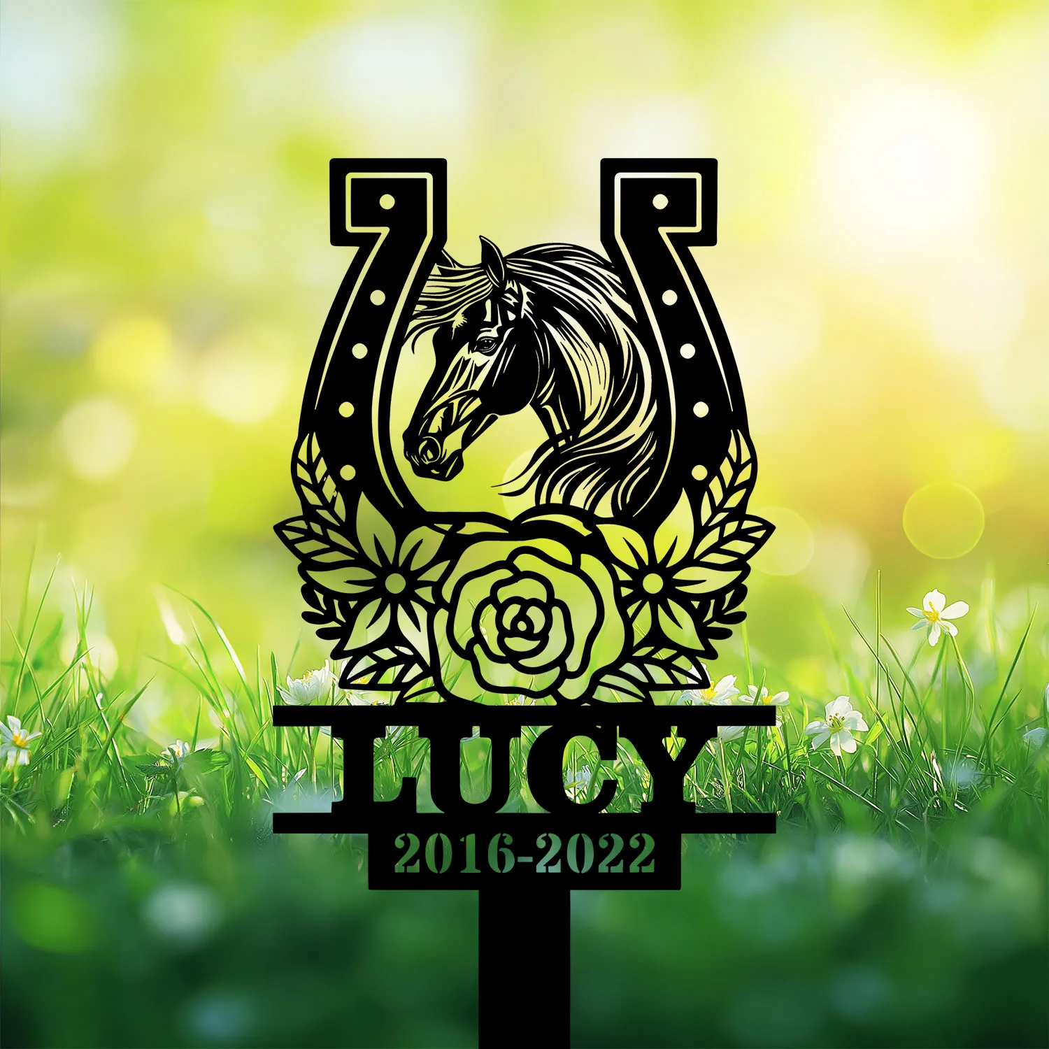 Style-20-horse-head-2-1 Black metal grave marker silhouette of a horse head inside a horseshoe with floral wreath, name LUCY and years 2016-2022 against sunlit grassy background