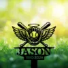 Black metal yard sign with winged baseball glove, ball and crossed bats above the name "JASON" and years "1990-2026" set against sunlit grassy background