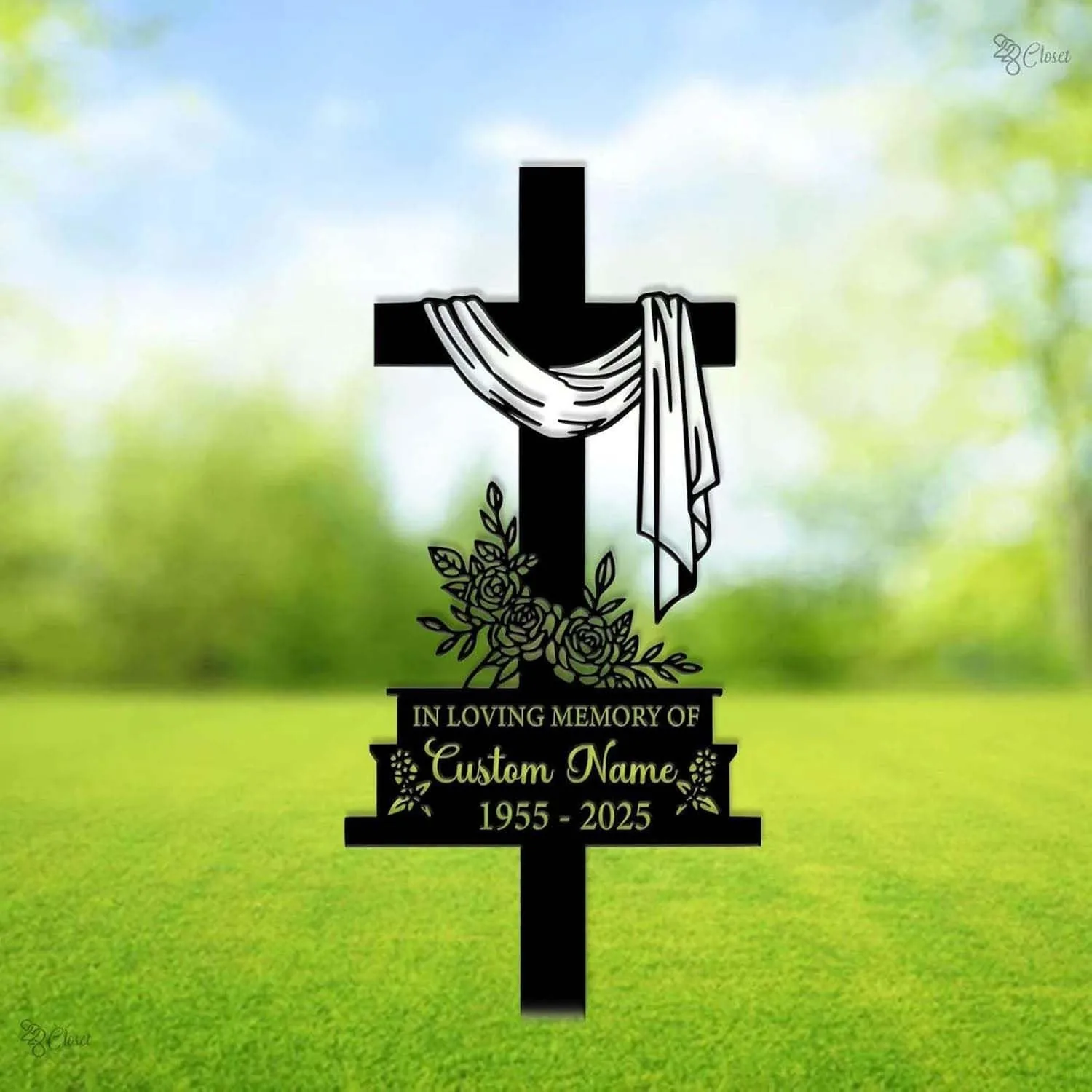 Black memorial cross sign in a green lawn with white draped cloth, floral design and text reading "In Loving Memory of Custom Name 1955 - 2025"