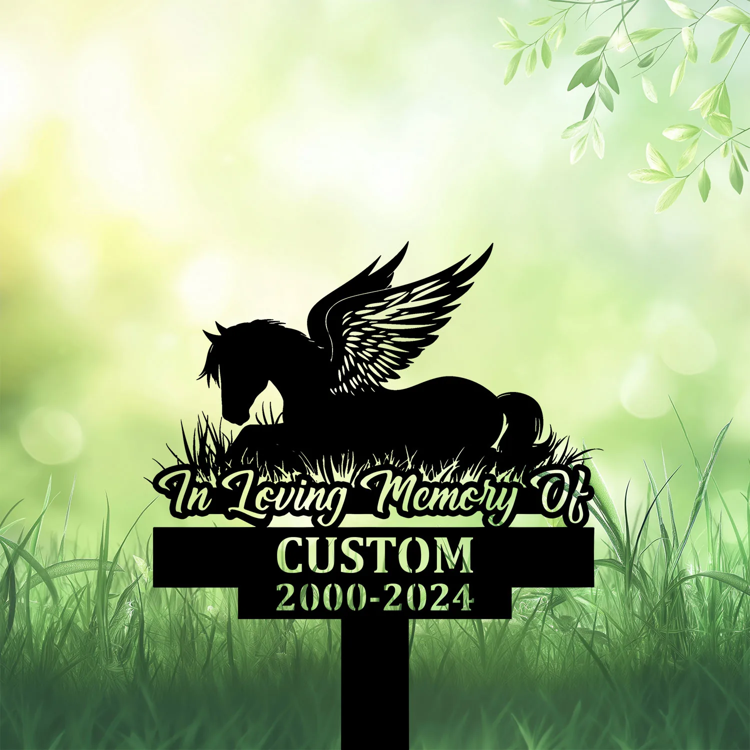 Silhouette memorial sign in grass with winged horse lying down and text "In Loving Memory Of" above customizable name and dates 2000-2024 on green bokeh background