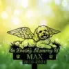 Green memorial sign with winged dog illustration and text "In Loving Memory Of MAX 2016–2024" on grass with bokeh background