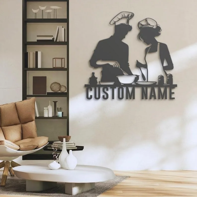 Modern living room wall metal art of two chefs cooking with placeholder text 'CUSTOM NAME' beside a shelving unit and cozy chair