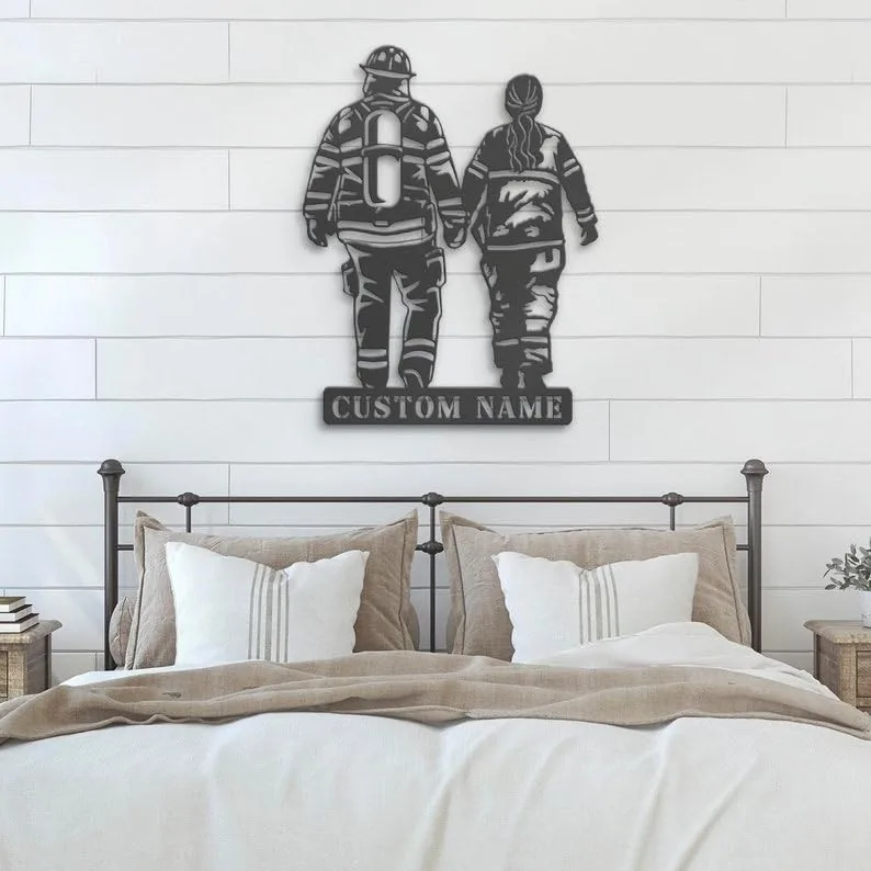 Black metal wall art of two firefighters holding hands with a 'CUSTOM NAME' plaque, mounted above a neutral farmhouse bedroom bed on white shiplap wall