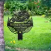style-17.-Riding-in-Heaven-1 Black metal memorial sign in a grassy garden reading "Riding in Heaven" with name Russel Smith and years 1963–2025, motorcycle silhouette and wings