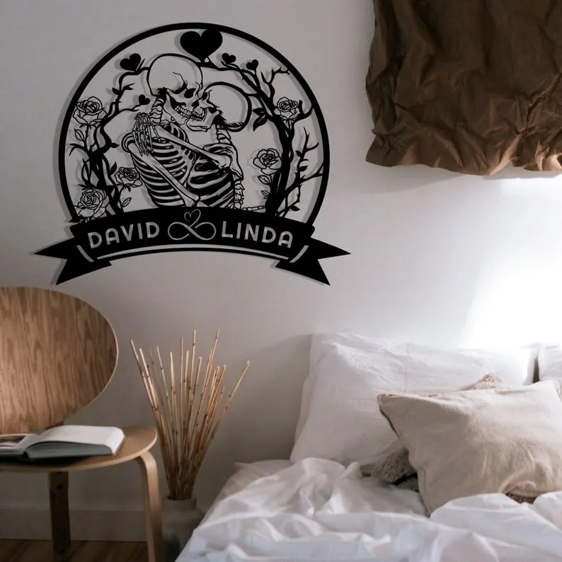 Black circular wall decal of two embracing skeletons surrounded by roses and hearts with banner reading 'DAVID ♥ LINDA' above a cozy bed and chair