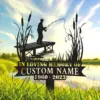 Memorial yard sign silhouette of a fisherman on a dock with cattails and text reading "IN LOVING MEMORY OF" and customizable name and years 1960 - 2023 against a sunny lake background
