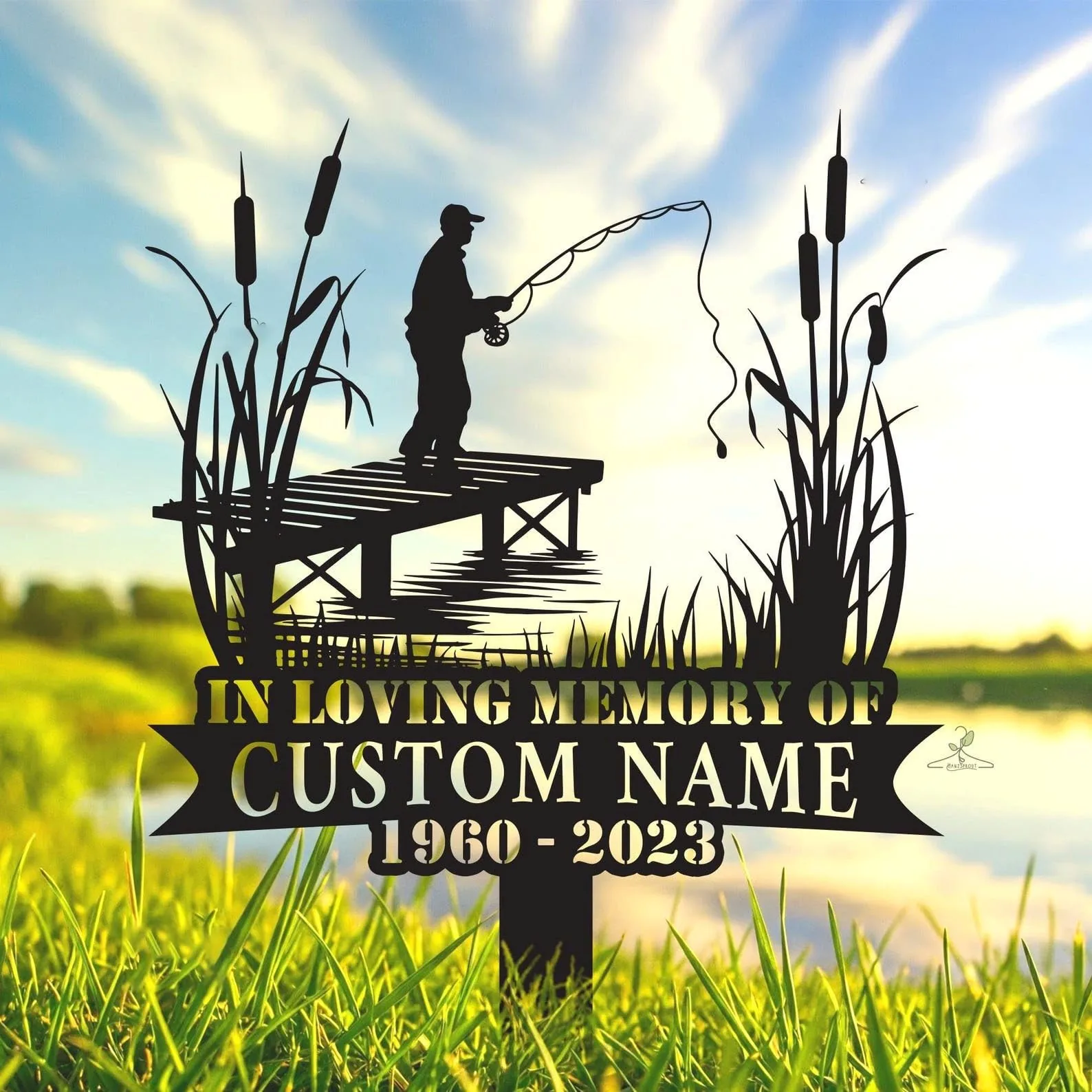 Memorial yard sign silhouette of a fisherman on a dock with cattails and text reading "IN LOVING MEMORY OF" and customizable name and years 1960 - 2023 against a sunny lake background