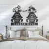 Metal wall art of two people riding ATVs fist-bumping above a customizable "CUSTOM NAME" sign, mounted above a farmhouse-style bed in a neutral bedroom
