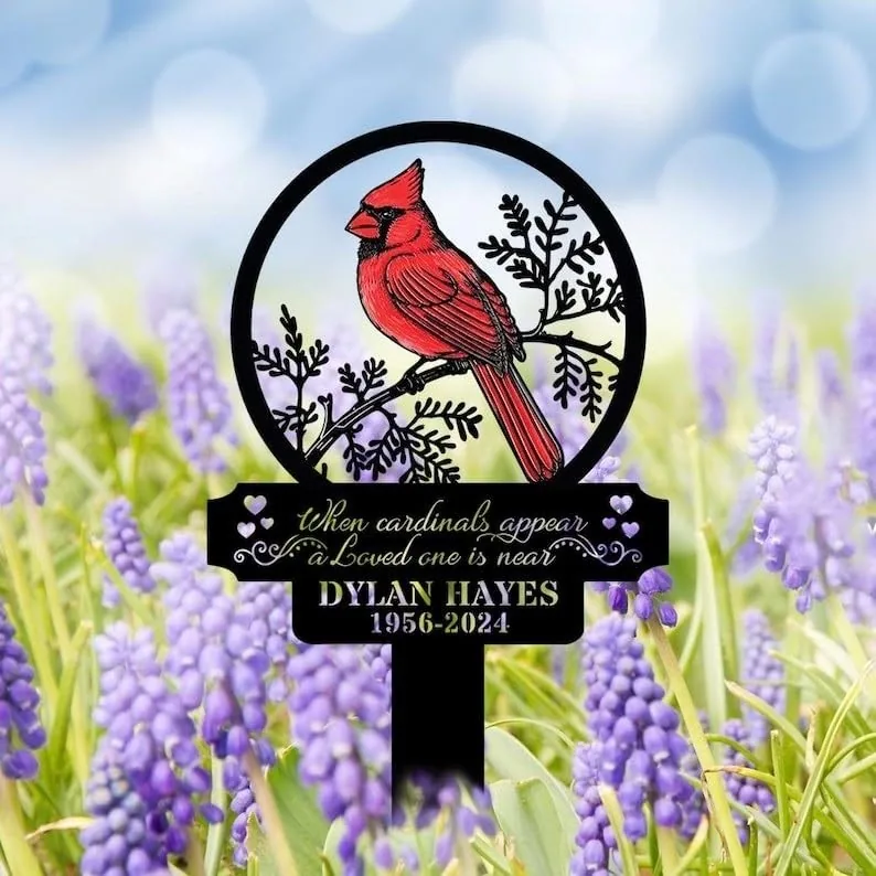 Garden memorial stake with a red cardinal illustration and text “When cardinals appear a loved one is near” above a name and dates, placed among purple flowers