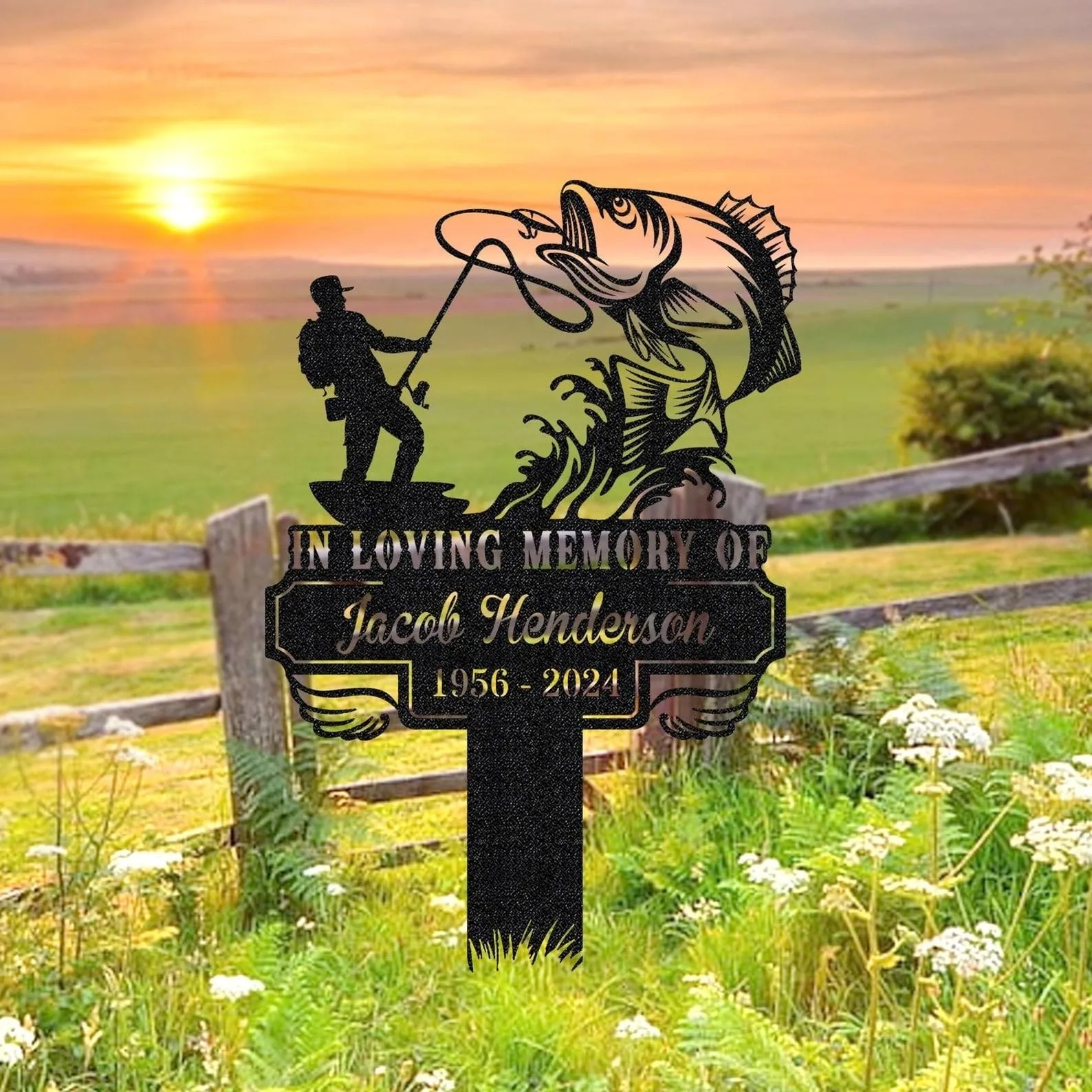 Metal memorial yard sign with fisherman catching a large fish reading “In Loving Memory of Jacob Henderson 1956 - 2024” set in a grassy field at sunrise