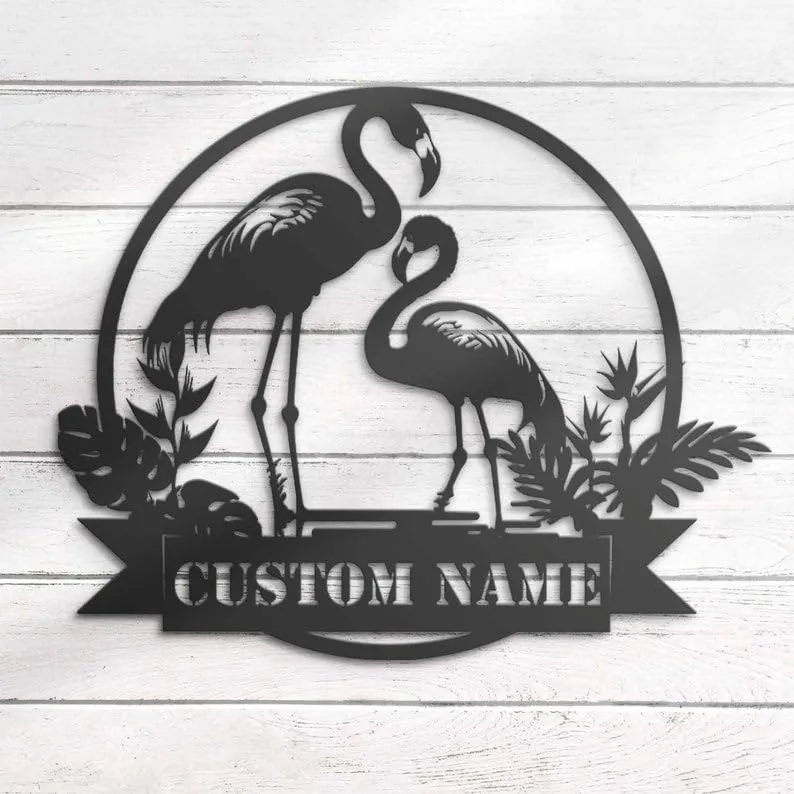 style-8.-Flamingo-Couple-1 Black metal wall art of two flamingos in a circular frame with tropical leaves and a ribbon reading 'CUSTOM NAME' mounted on white shiplap