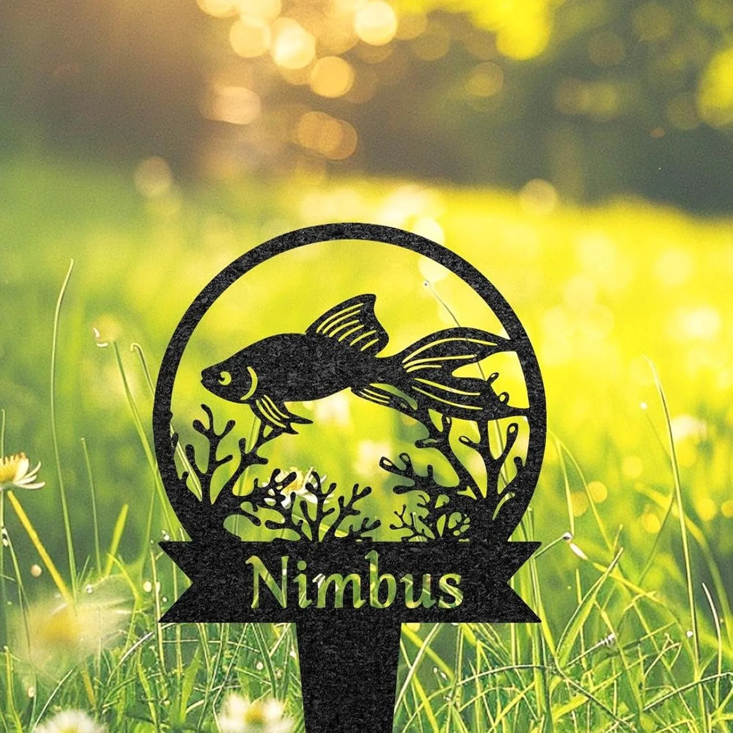 Black metal garden stake with a fish and coral silhouette and the name "Nimbus" against a sunlit grassy background