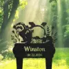 Black silhouette garden sign with a badger and plants above the name 'Winston' and date '08.22.2024' set against a sunlit forest background
