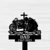 Black silhouette memorial sign showing a motorcyclist kneeling by a cross beside a sportbike with text "In Loving Memory Of DAD 1967-2025" on a light wood plank background