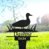 Black metal yard stake with a duck silhouette, grass details and the name "Daphne" with "2024" placed in a sunny lawn setting