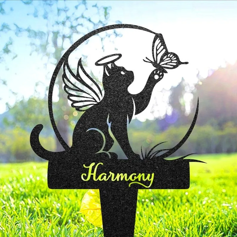 Black garden stake silhouette of a winged cat with halo reaching for a butterfly above the word "Harmony" set in grassy backyard with sunlight