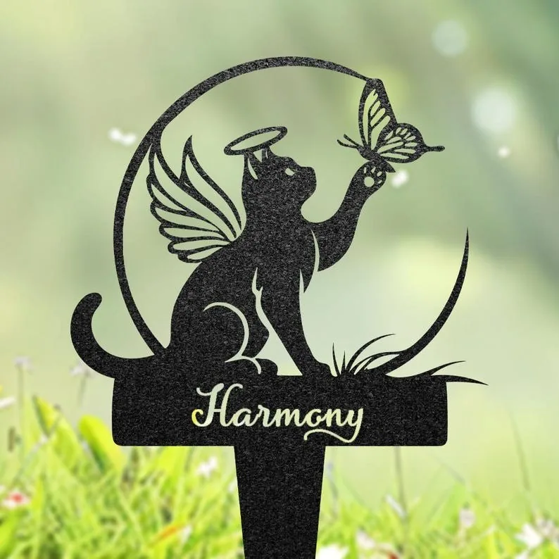 Black garden stake silhouette of a winged, haloed cat reaching for a butterfly with the word "Harmony" on a grassy blurred background
