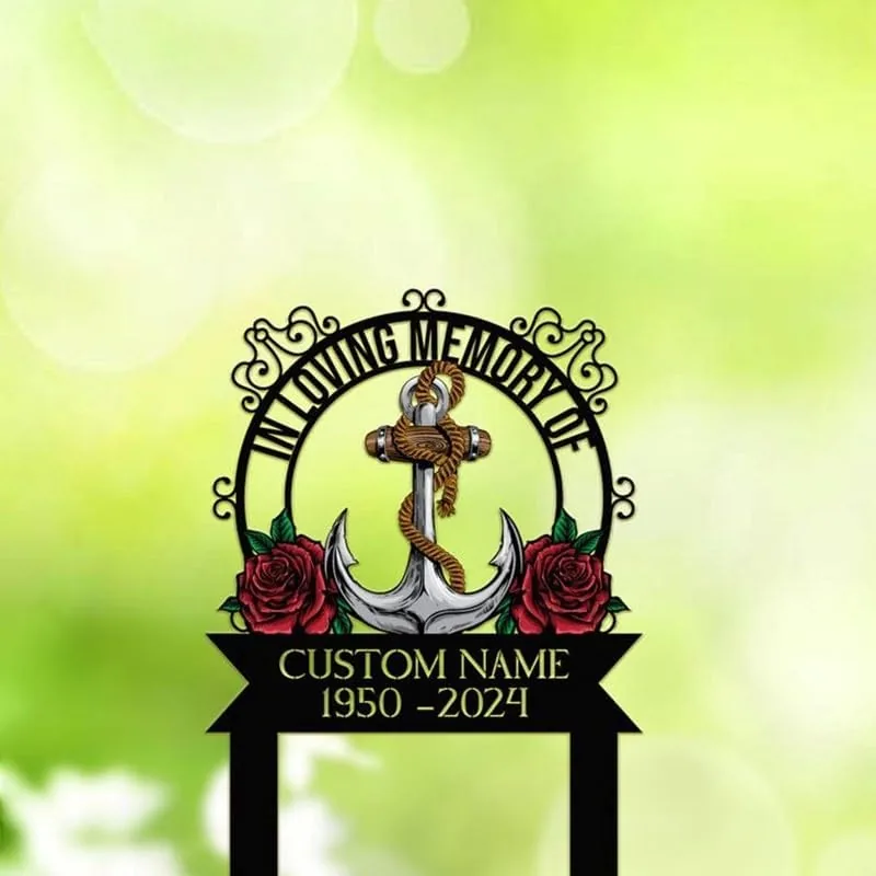 Black memorial sign reading "In Loving Memory" with an anchor wrapped in rope, red roses and a banner showing "Custom Name 1950-2024" against a soft green bokeh background
