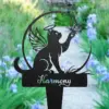 Black garden stake silhouette of a winged cat with halo reaching for a butterfly, word "Harmony" on the base against a blurred flowered garden path