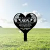 Black heart-shaped memorial stake in a grassy field reading "In loving memory SON" with angel wings, poem lines and name "Jack Anderson 1990 - 2023"
