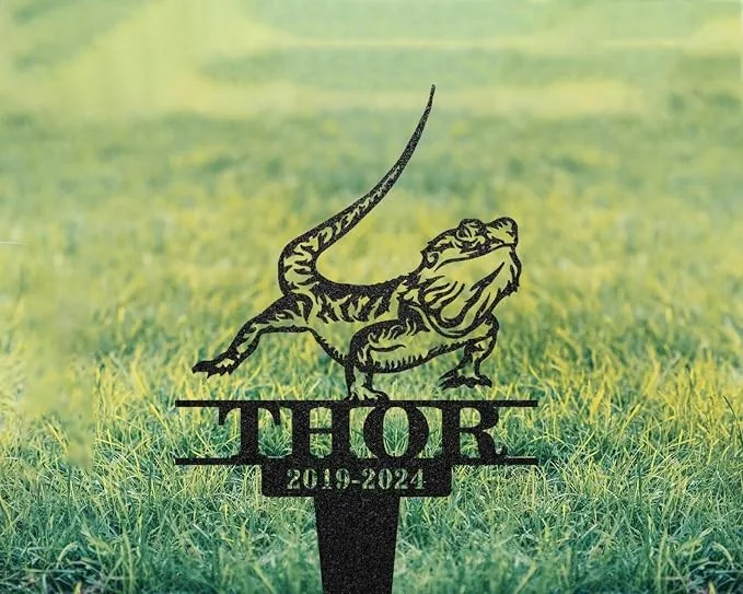 Black metal yard sign of a bearded dragon lizard above the name THOR and dates 2019-2024 placed in a grassy lawn