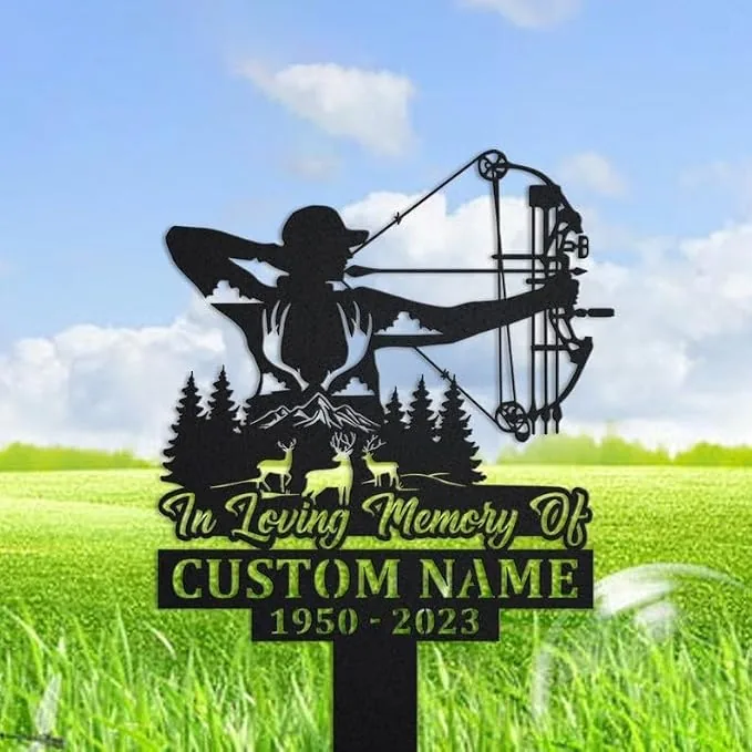 Black metal memorial yard sign showing a silhouette of an archer with a compound bow, pine trees, deer and mountains, reading “In Loving Memory Of CUSTOM NAME 1950 - 2023,” placed in a grassy field under a blue sky.