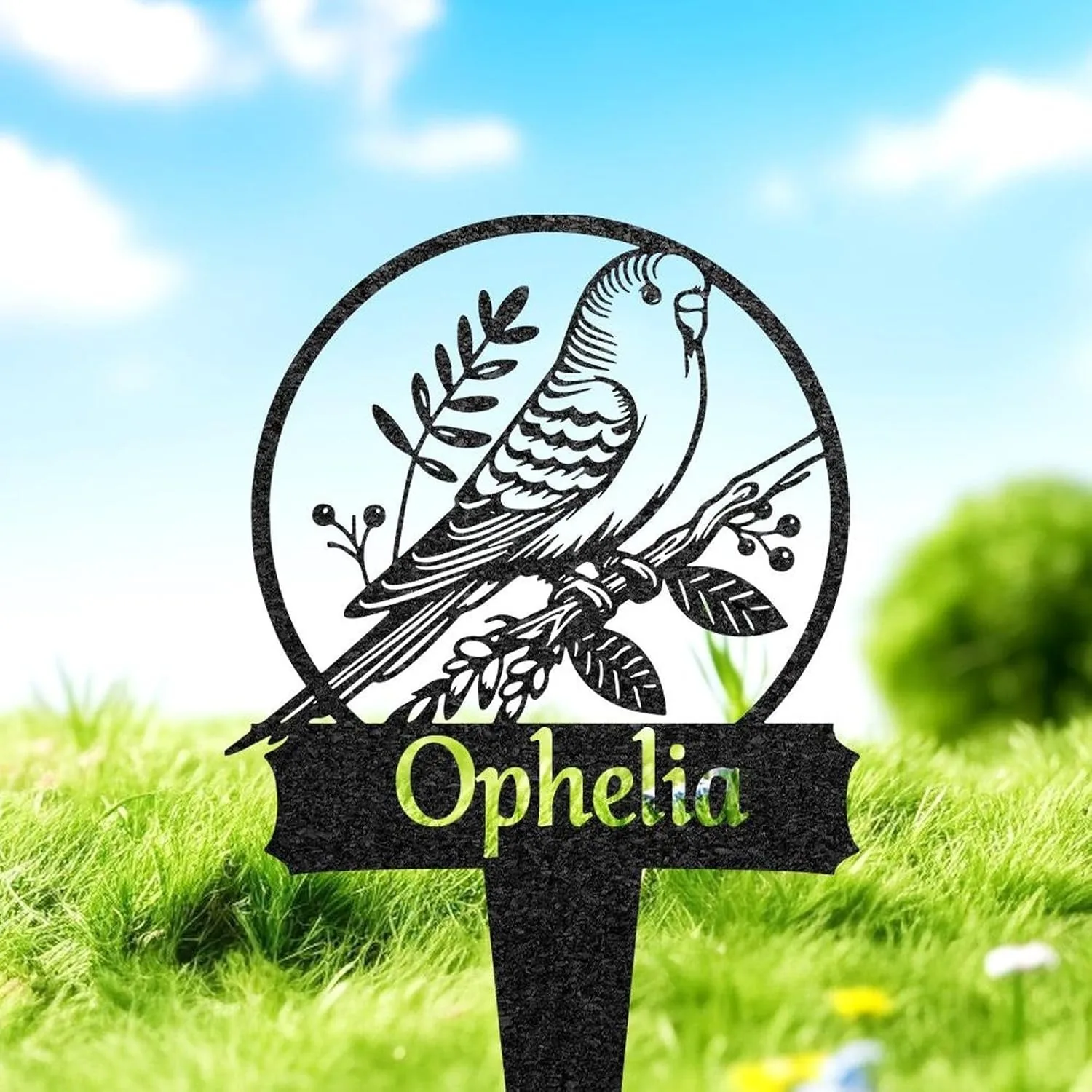 Black metal garden stake with a perched bird inside a circular frame and the name "Ophelia" displayed below, shown in grassy outdoor setting