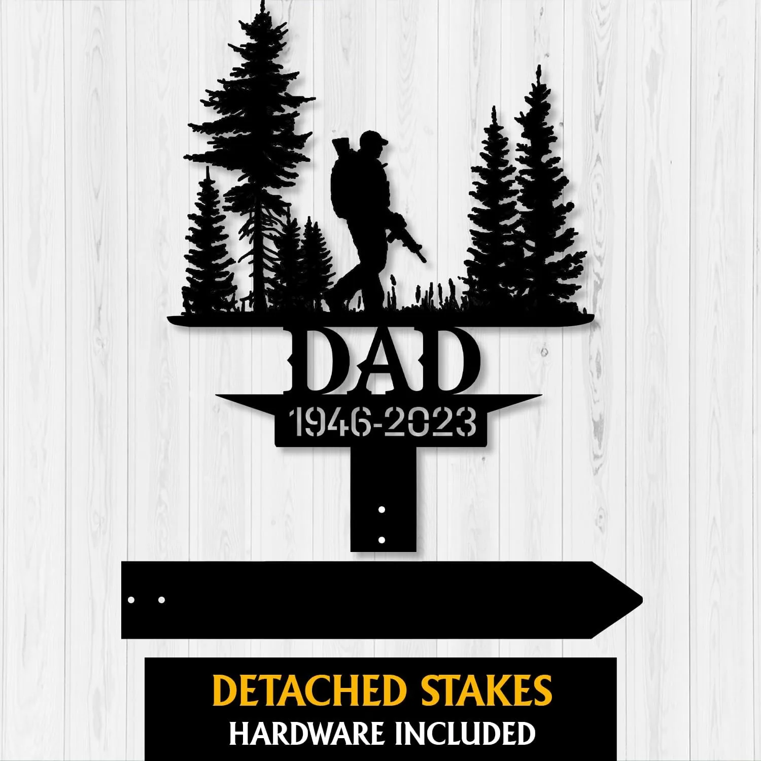 Black metal memorial sign showing a hunter silhouette walking with a rifle among pine trees, text "DAD" and dates "1946-2023" on a white wood background