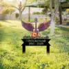 241-2 Outdoor memorial yard sign in grass showing a winged acoustic guitar and text "In Loving Memory Of" with placeholder "CUSTOM NAME 1950-2024" near a picnic shelter
