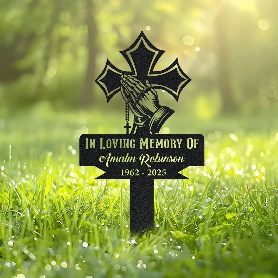 252-1 Black cross grave sign on grassy lawn reading "In Loving Memory Of Amalun Robinson 1962 - 2025" with praying hands and rosary design