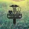 Metal memorial garden stake with caduceus, stethoscope, heart with EKG line, text reading "In Loving Memory of" and placeholders for custom name and dates, placed in grassy field