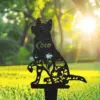 Black metal silhouette of a sitting cat with floral cutouts and the name 'Coco', planted stake in a sunny green lawn