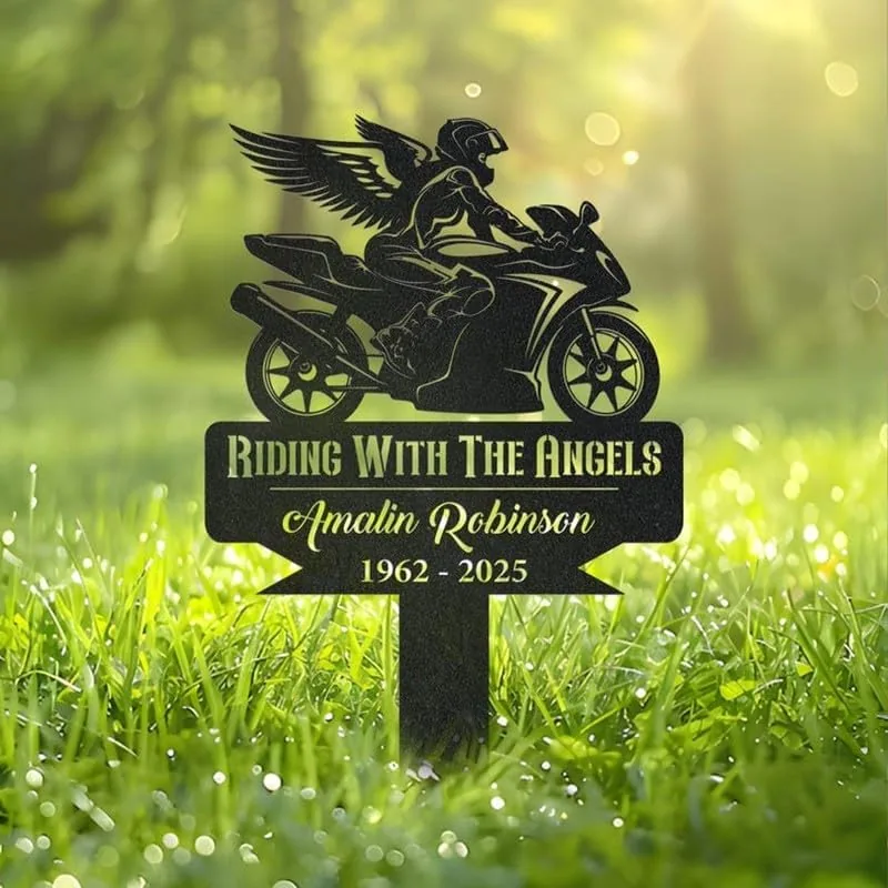 Black metal grave marker in grass showing a winged motorcyclist and text “Riding With The Angels, Amalin Robinson, 1962 - 2025”