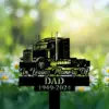 Black memorial yard sign with a semi truck silhouette reading "In Loving Memory Of" and "DAD 1949-2024" placed among daisies in a sunlit garden