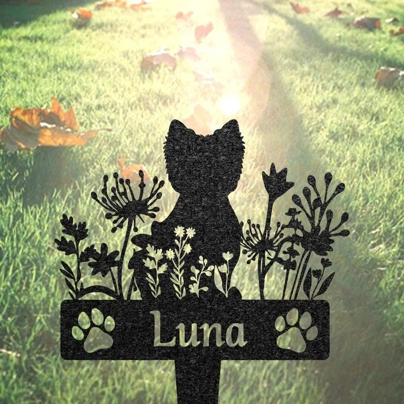 Black metal garden stake silhouette of a cat amid wildflowers with paw prints and the name "Luna" against sunlit grass
