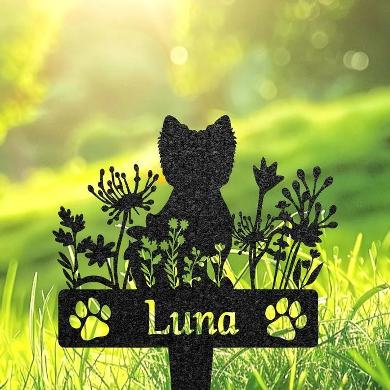Black metal garden silhouette of a cat among flowers with the name "Luna" and paw prints, staked in sunlit green grass