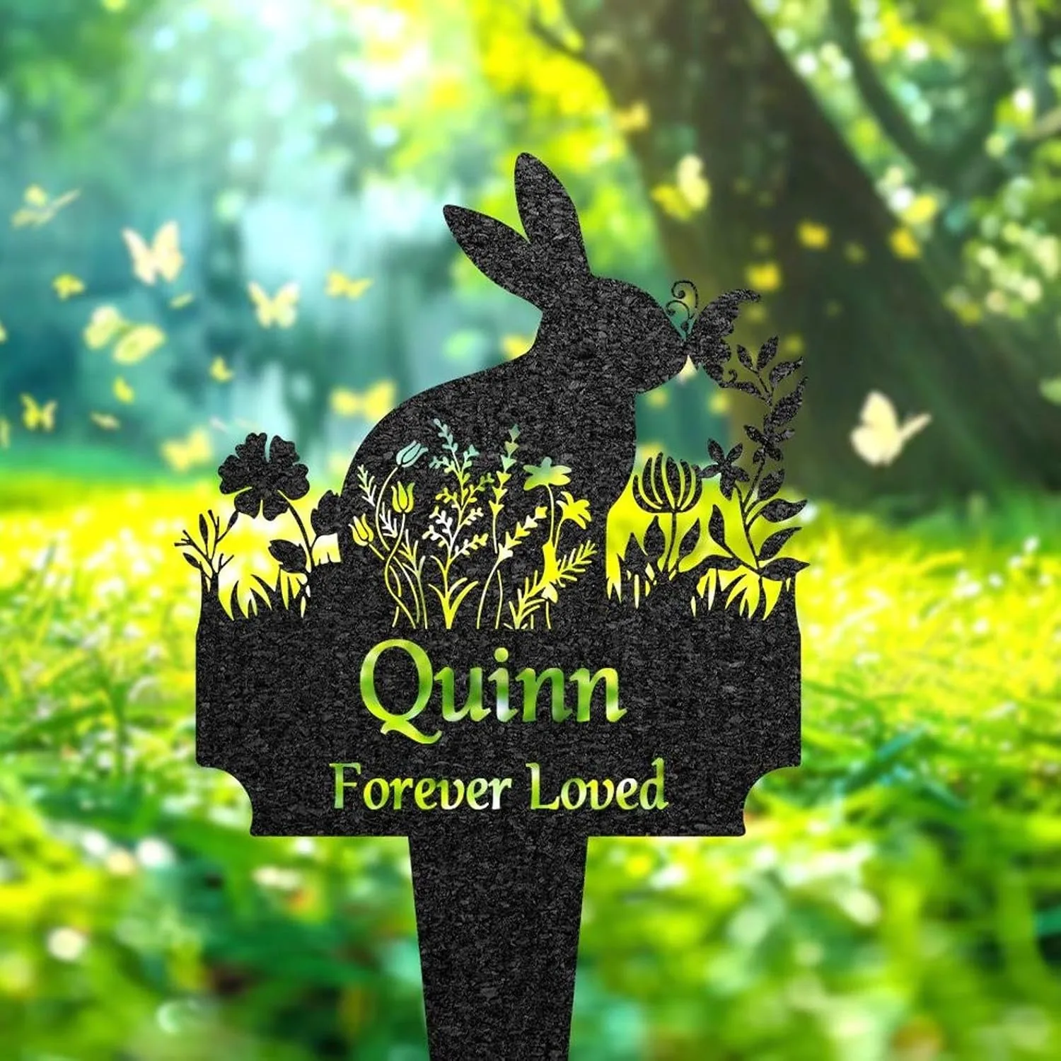 31-2 Black garden stake shaped like a rabbit with floral cutouts and text 'Quinn Forever Loved' against a sunlit green meadow background