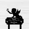 Black silhouette memorial plaque of a winged baby reaching for a butterfly with text "I'll hold you in my heart until I can hold you in heaven 2026" on a white wood background