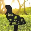 Silhouette metal garden stake in the shape of a sitting dog with floral cutouts and the name "Jinx", placed in sunlit grassy yard