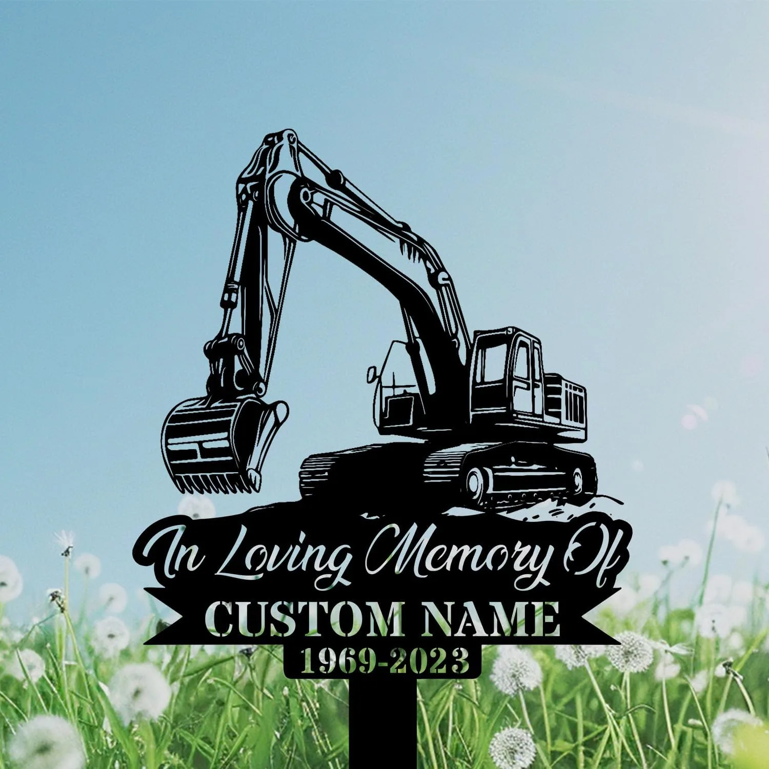 Black silhouette memorial sign of an excavator over text reading 'In Loving Memory Of' and placeholder 'CUSTOM NAME 1969-2023' set against a grassy field with dandelions and blue sky
