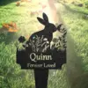 32-2 Black metal garden memorial stake shaped like a rabbit with floral cutouts and text reading "Quinn Forever Loved" placed in sunlit grass