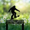 Black silhouette of a snowboarder above daisies with a decorative memorial sign reading "FOREVER LOVED NAME 1986-2025" against a soft green bokeh background