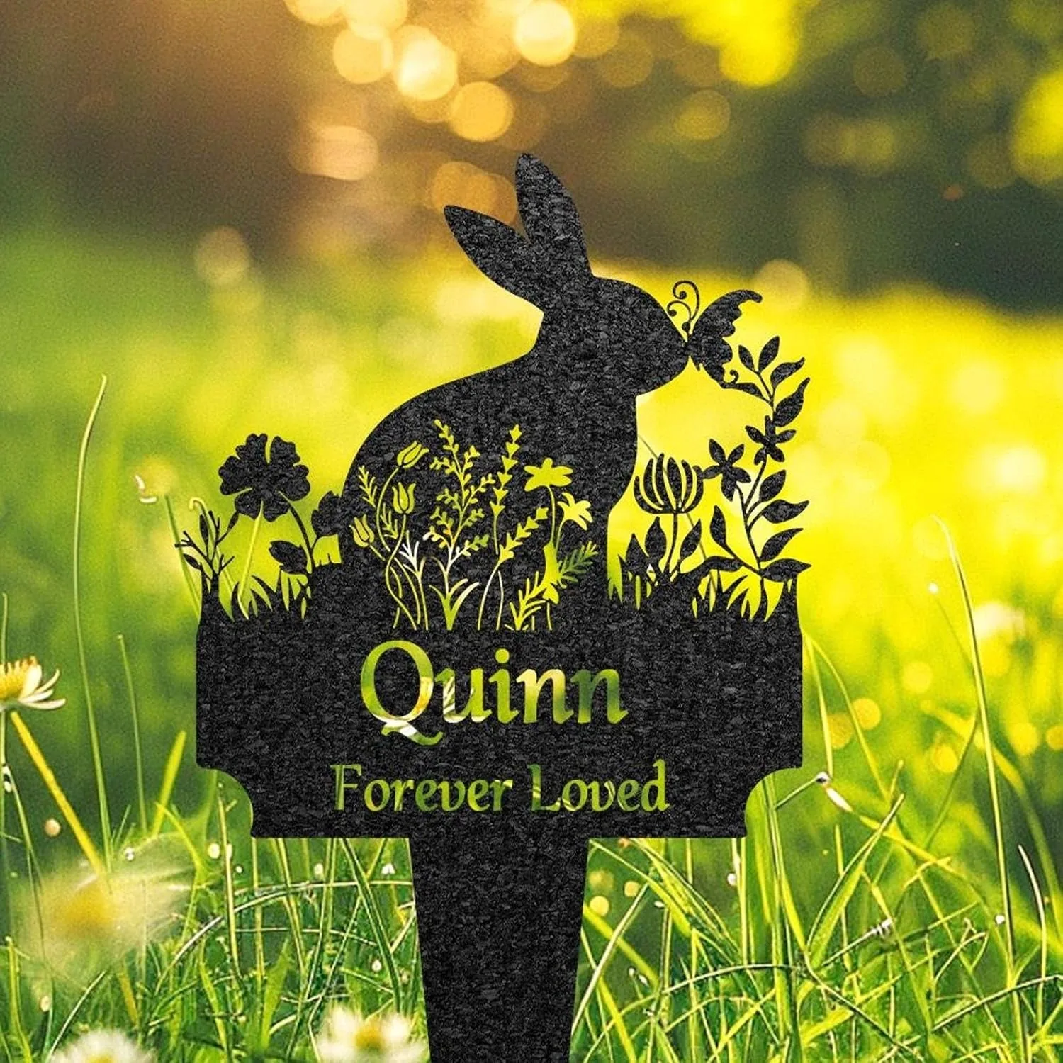 33-2 Black garden memorial stake shaped like a rabbit with floral cutouts and the name "Quinn" and phrase "Forever Loved" against sunlit grassy background