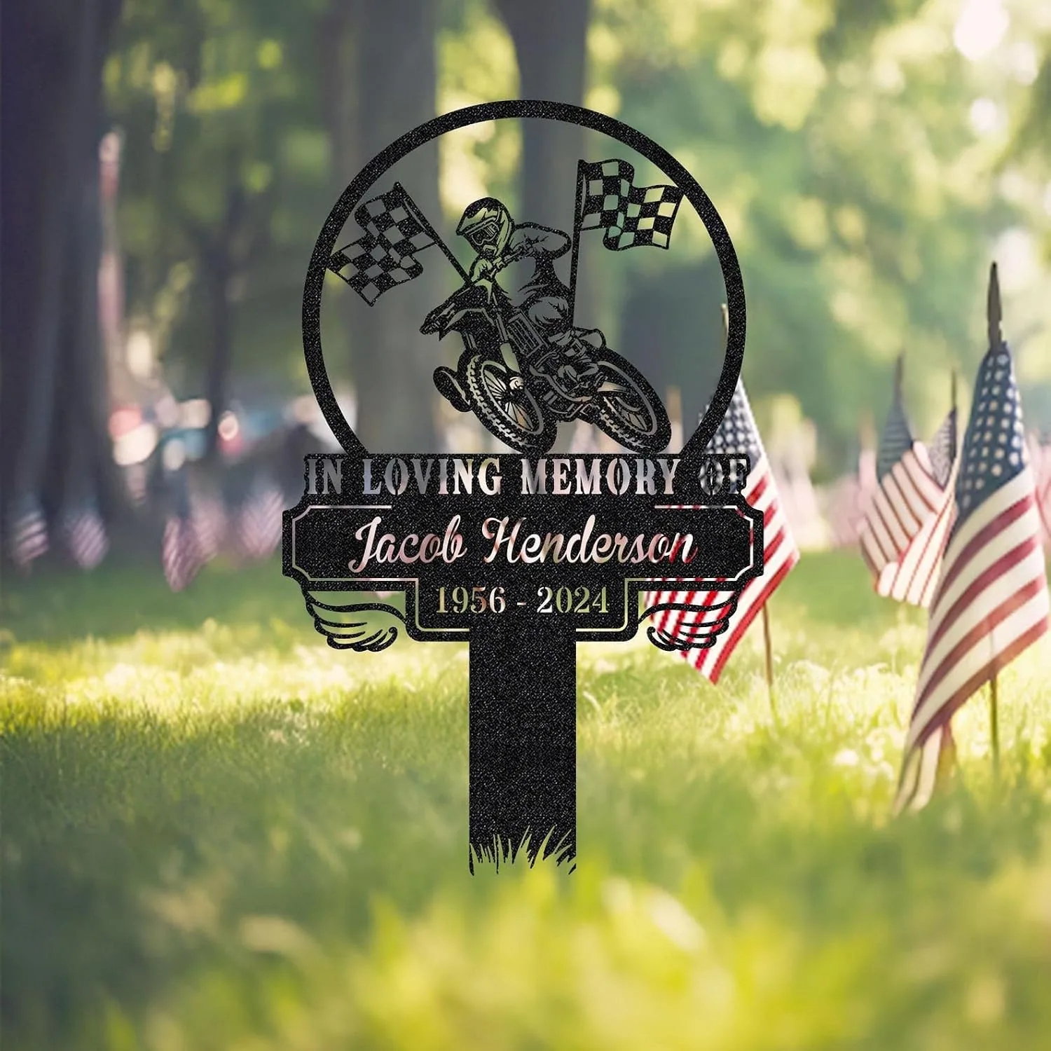 352 Memorial yard sign in grass with American flags, black silhouette of motocross rider and checkered flags and text “In Loving Memory of Jacob Henderson 1956 - 2024”