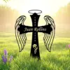 Black angel wing cross garden stake with halo reading "Juan Rollins" and dates 1980–2025 set in a sunlit grassy field with purple flowers