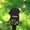 Black metal silhouette garden stake of a sitting dog with floral cutouts and the name 'Willow' against sunlit green grass