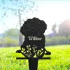 Black metal garden silhouette of a sitting dog with floral cutouts and the name "Willow," staked in sunlit grass