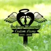 Black memorial lawn stake with angel wings, heart with baby footprints and halo reading "In Loving Memory Of" and "Custom Name" with years 2020 - 2025 on green grassy background