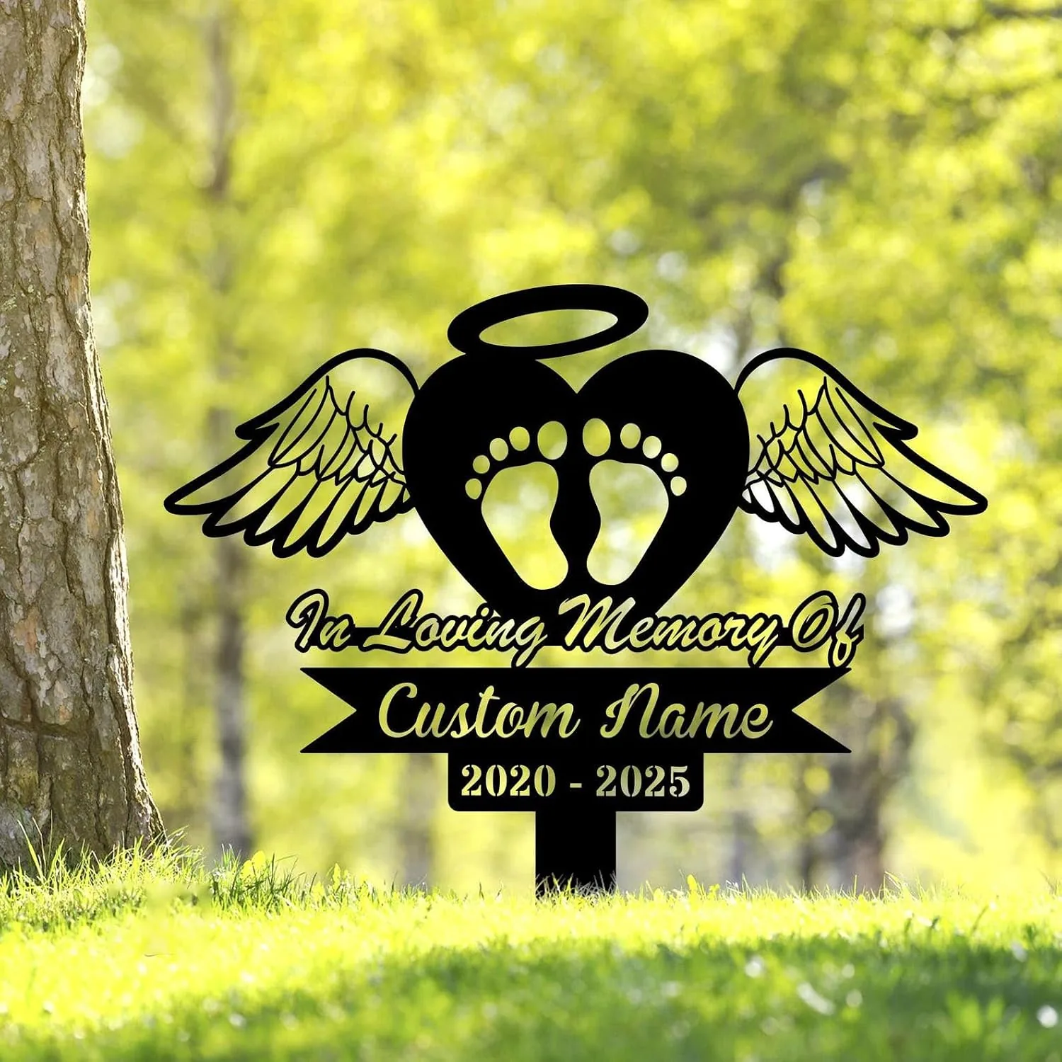 Black memorial yard sign with angel wings, heart and baby footprints reading "In Loving Memory Of" and customizable name with dates 2020 - 2025 in a grassy outdoor setting